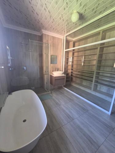 a bathroom with a large white tub and a sink at The Second Tranquilo in Ermelo