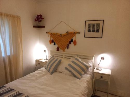 a bedroom with a white bed with two nightstands and two lamps at Bird cottage in Barrydale