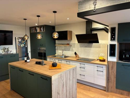 a kitchen with green cabinets and a wooden island at Location de Chambre SDB Cuisines in Charleroi