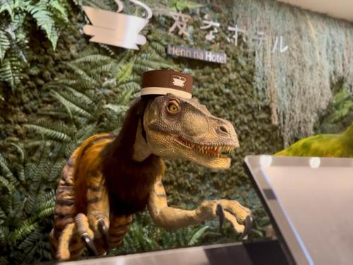 a toy dinosaur wearing a hat next to a laptop at Henn na Hotel Maihama Tokyo Bay in Urayasu