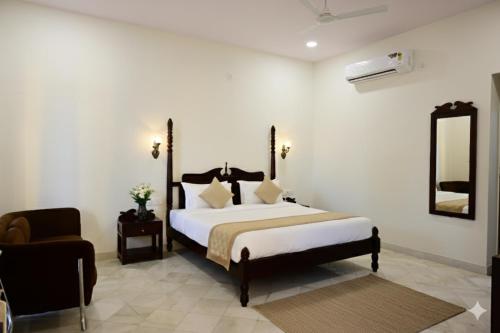 a bedroom with a bed and a chair and a mirror at Achal Bagh - Boutique Stay Abu Road in Māwāl