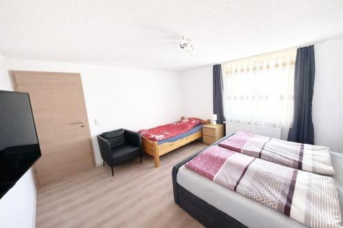 a bedroom with a bed and a chair and a television at FERIENHAUS AyNa, direkt an der Schweizer Grenze in Bad Säckingen