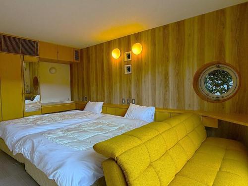 a bedroom with a large bed and a yellow couch at 熱海ブレスアネックス in Atami
