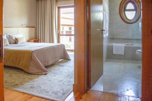 a bedroom with a bed and a bathroom with a tub at Hotel Rural Casa de Samaioes in Chaves