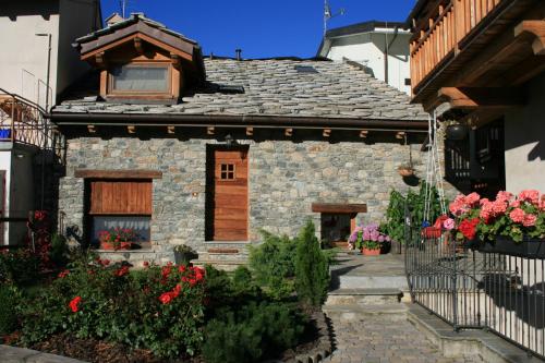 une maison en pierre avec des fleurs devant elle dans l'établissement B&B Lo Tatà, à Fenis