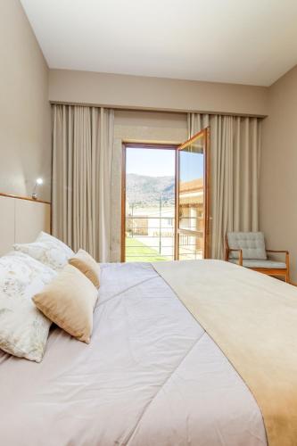 a bedroom with a large bed with a large window at Hotel Rural Casa de Samaioes in Chaves