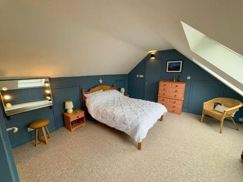 a bedroom with a bed and a blue wall at Saddle Cottage in Penzance