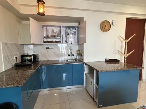 a kitchen with blue cabinets and a clock on the wall at Azure by Grehstay in Noida