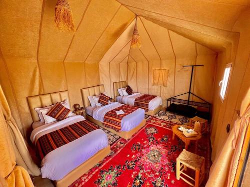 a room with two beds and a red rug at Big Dipper Luxury Camp in Merzouga