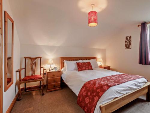 a bedroom with a large bed and a chair at 3 Bed in Bideford oc-05171 in Woolfardisworthy