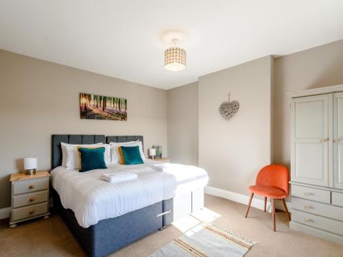 a bedroom with a large bed and a orange chair at 3 Bed in York oc-79525 in Deighton