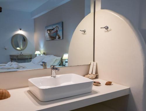 a bathroom with a sink in front of a mirror at Giasemi Rooms in Livadi Astypalaias