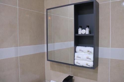 a mirror in a bathroom with towels on a shelf at Maya Villa in Oyibi