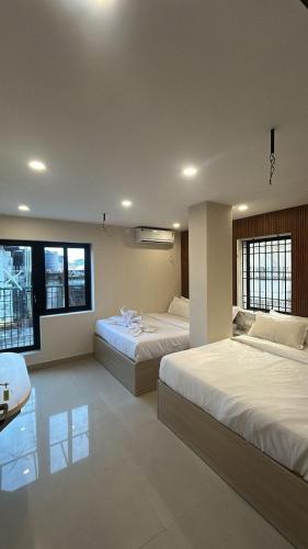 a bedroom with two beds and two windows at Tresor Hotel in Cochin