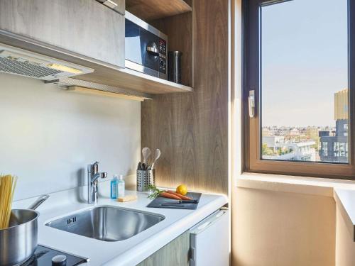 a small kitchen with a sink and a window at AppartHotel Mercure Paris Boulogne in Boulogne-Billancourt