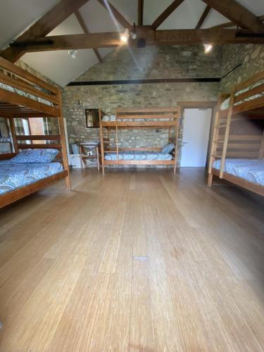 a room with three bunk beds and a wooden floor at Magdalen The Old Dairy in Winsham