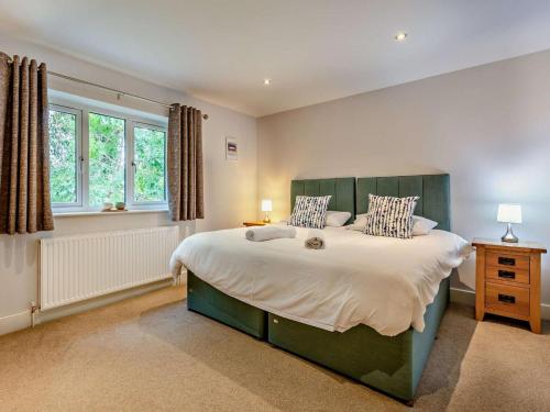 a bedroom with a large bed and two windows at 5 Bed in Braunton oc-78250 in Braunton