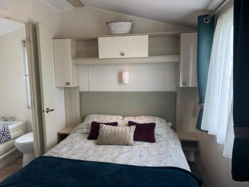 a small bedroom with a bed with purple pillows at Northcott 59, Bude in Poughill