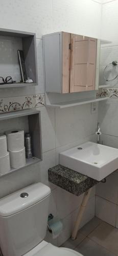 a white bathroom with a sink and a toilet at Casa reformada com Wi-Fi, garagem e lavanderia in Capão da Canoa