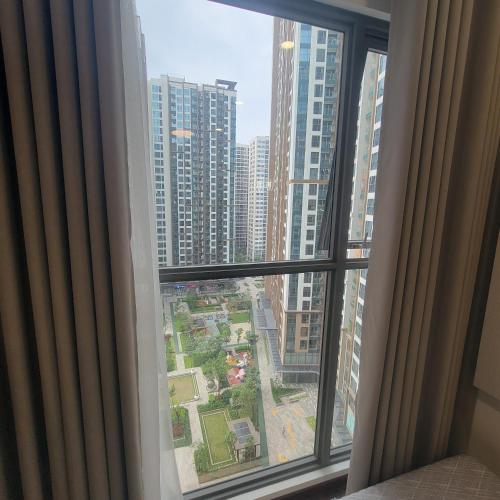 a window with a view of a city with tall buildings at H3 ocean park 1 in Gia Lâm Pho