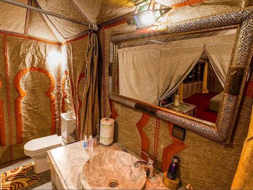 a bathroom with a sink and a toilet and a mirror at Maria'S Luxury Camp in Merzouga