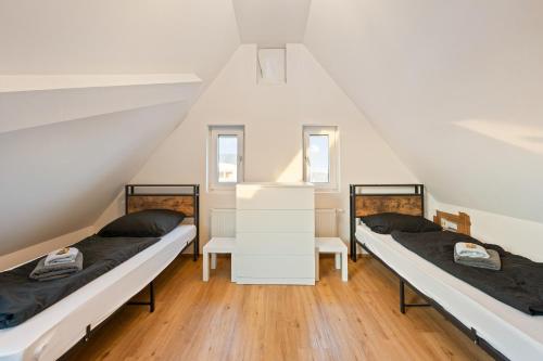 two beds in a attic bedroom with white walls at Monteurzimmer Haus 6 Nebringen für bis zu 12 Personen - Küche und Parkplätze vorhanden in Gäufelden