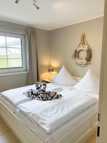 a bedroom with a large white bed with a window at Amselkoje in Süderende