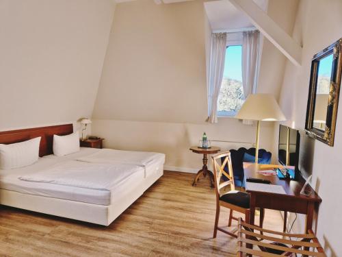 a bedroom with a bed and a desk and a window at Hotel Villa Viktoria Luise in Blankenburg