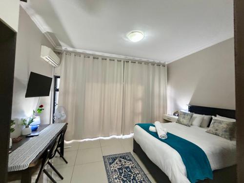 a bedroom with a bed and a desk and a window at Meridian Suite Apartments in Umhlanga Ridge in Durban