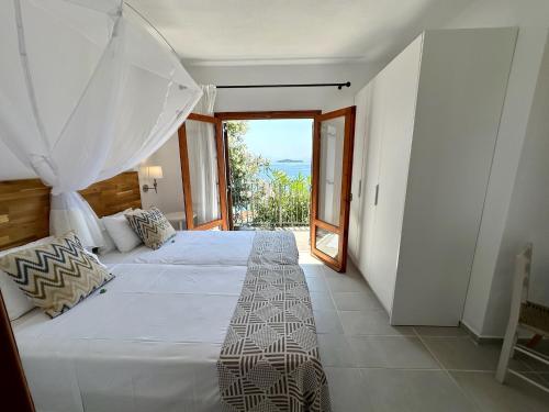 a bedroom with a large white bed and a balcony at Villa Athena Skiathos in Megali Ammos