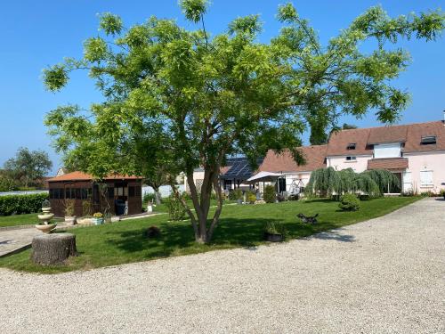 a tree in a yard next to a building at Une parenthèse fleurie in La Heunière