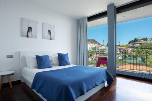 a bedroom with a blue bed and a large window at Villa Ocean Sight by LovelyStay in Funchal