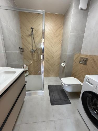 a bathroom with a shower toilet and a washing machine at Apartament Skarbowa East in Leszno