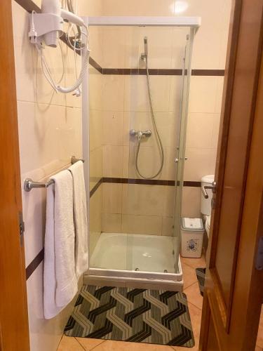 une douche avec une porte en verre dans une salle de bain dans l'établissement Apartamento espaçoso, à Santa Maria