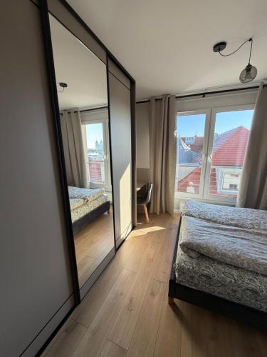 a mirror in a bedroom with a bed and a window at Apartament Skarbowa East in Leszno