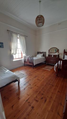 a bedroom with two beds and a wooden floor at House with Those Stairs in Langebaan