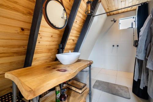 a bathroom with a mirror and a wooden wall at Canda Cabana com SPA e vista para Cachoeiras in Baependi
