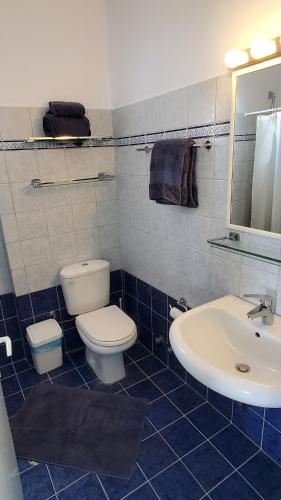 a blue tiled bathroom with a toilet and a sink at Villa E - Kamari Village in Kastraki