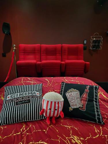 a red bed with pillows and a red couch at Hollywood Spa Jacuzzi - Cinéma in Château-Thierry