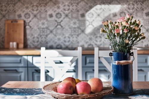 a table with a basket of apples and a vase with flowers at Domek Luna Wilcza Zagroda in Kudowa-Zdrój
