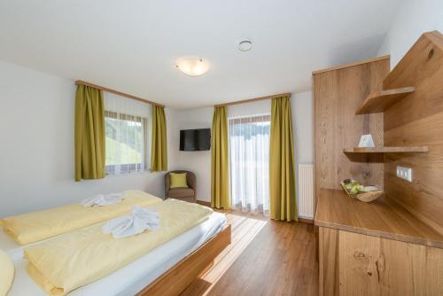 a bedroom with a large bed with yellow curtains at Pension Bergbauernhof Irxner in Schladming
