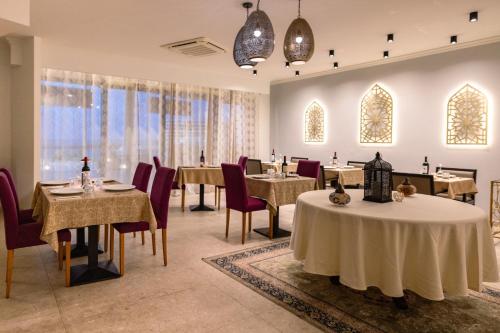 a dining room with tables and chairs and windows at Riviera Spa Resort - Adults Only in Mellieħa