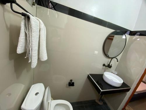 Un baño con lavabo, inodoro y espejo. en Studio triomphe, en Saly Portudal