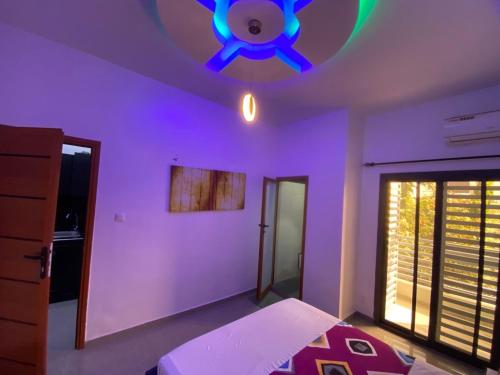 een slaapkamer met een paars plafond en een plafondventilator bij Studio triomphe in Saly Portudal