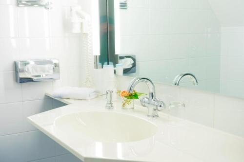 a white bathroom with a sink and a mirror at Hotel Villa Viktoria Luise in Blankenburg