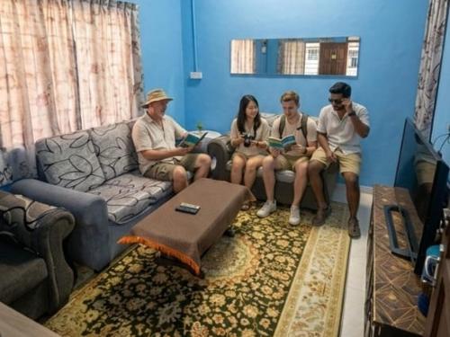 a group of people sitting on a couch in a living room at Hostel Qamaar in Langkawi Intl