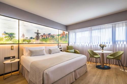 a bedroom with a large bed and a table and chairs at Barceló Malaga in Málaga