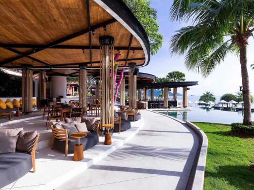a resort patio with tables and chairs and a pool at Pullman Phuket Panwa Beach Resort in Panwa Beach