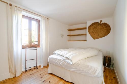 a white bedroom with a bed and a window at Maison avec jardin in Chirac