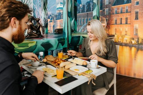 a woman sitting at a table with a tray of food at The Hague Teleport Hotel - Free Parking in The Hague